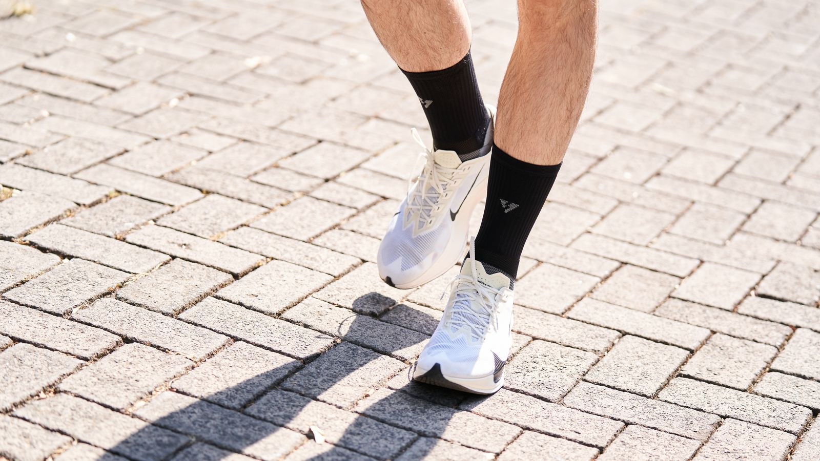 A person in running shoes walks along a paved path.