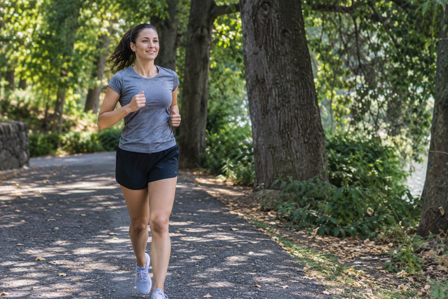 A recreational runner jogs along a shaded level path.