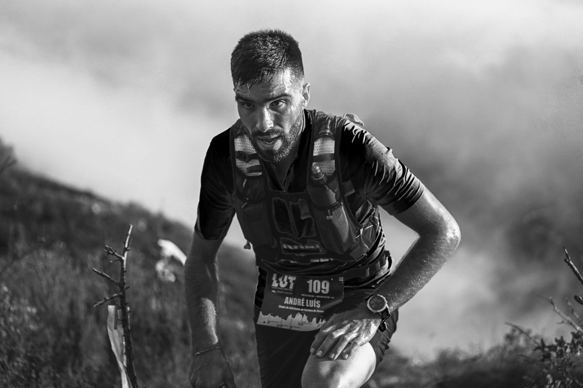 A trail participant leans forward while ascending a rocky slope.