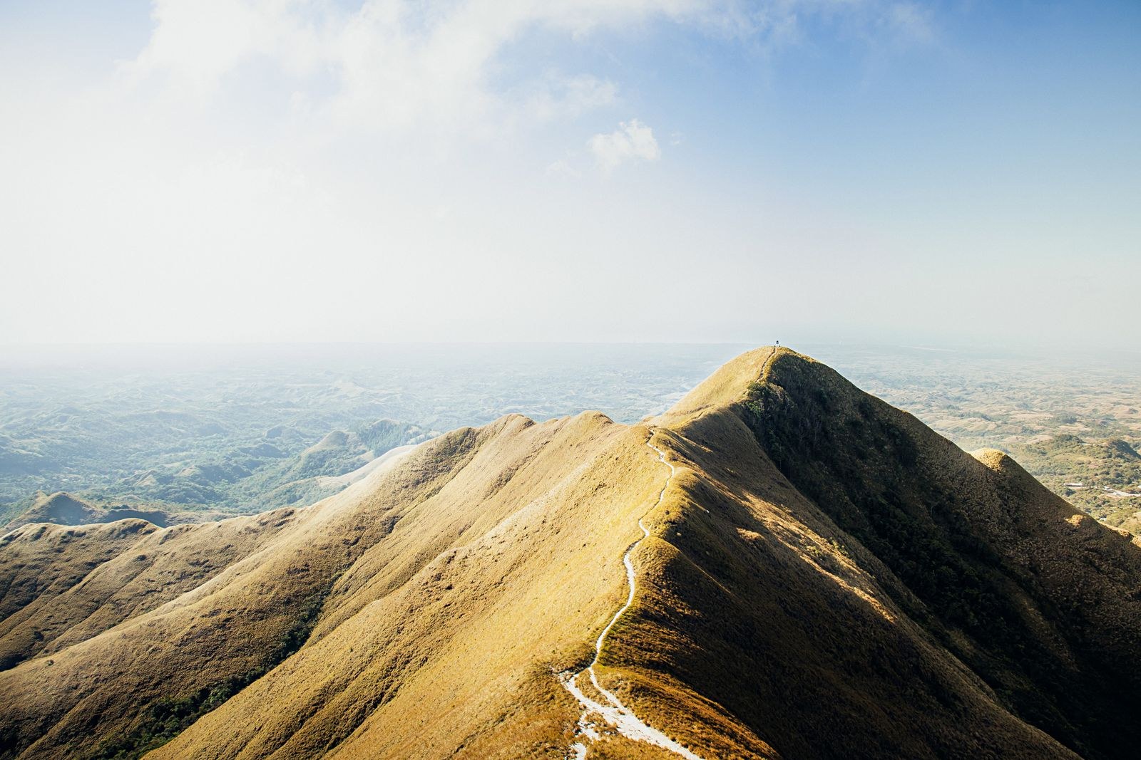A narrow path follows an exposed grassy mountain ridge.