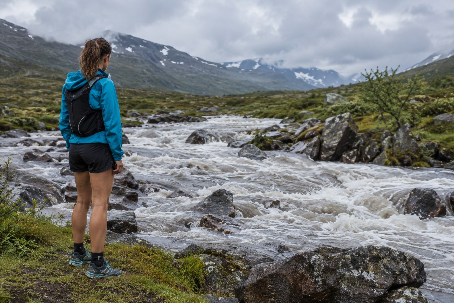 A runner stops back from a swollen stream crossing.