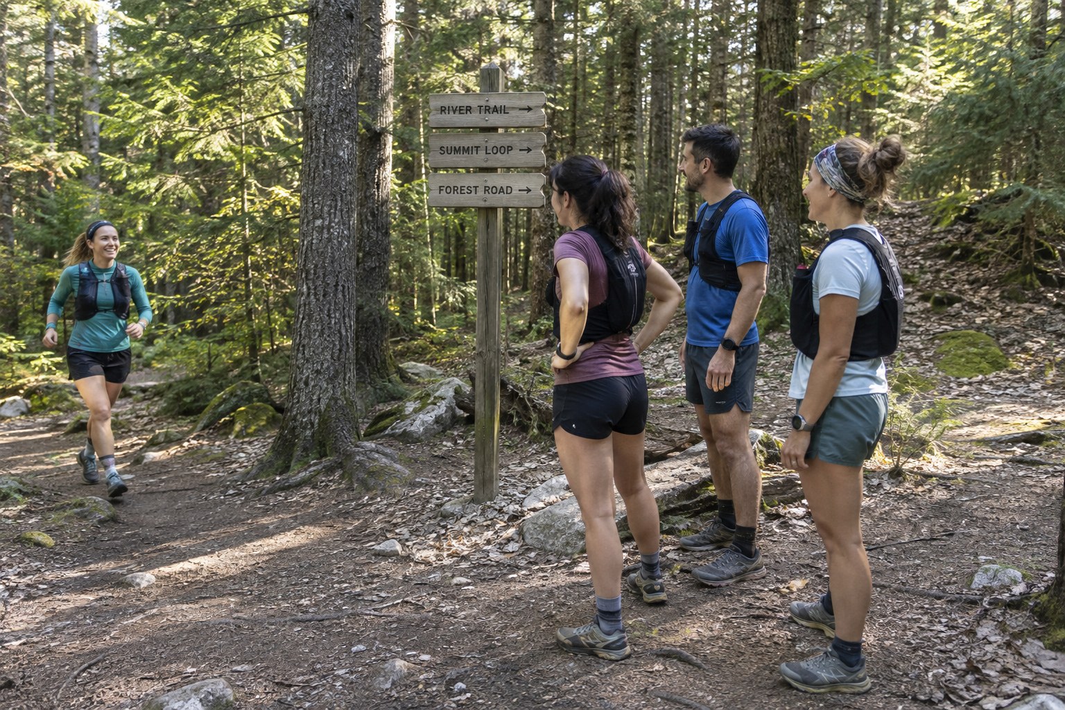 A group of runners waits together at a trail junction.