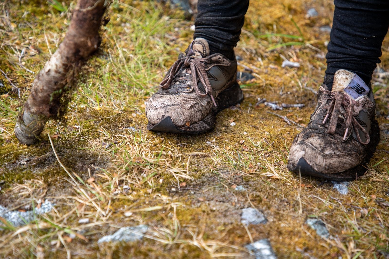 Mud covers the uppers and laces of two outdoor shoes.