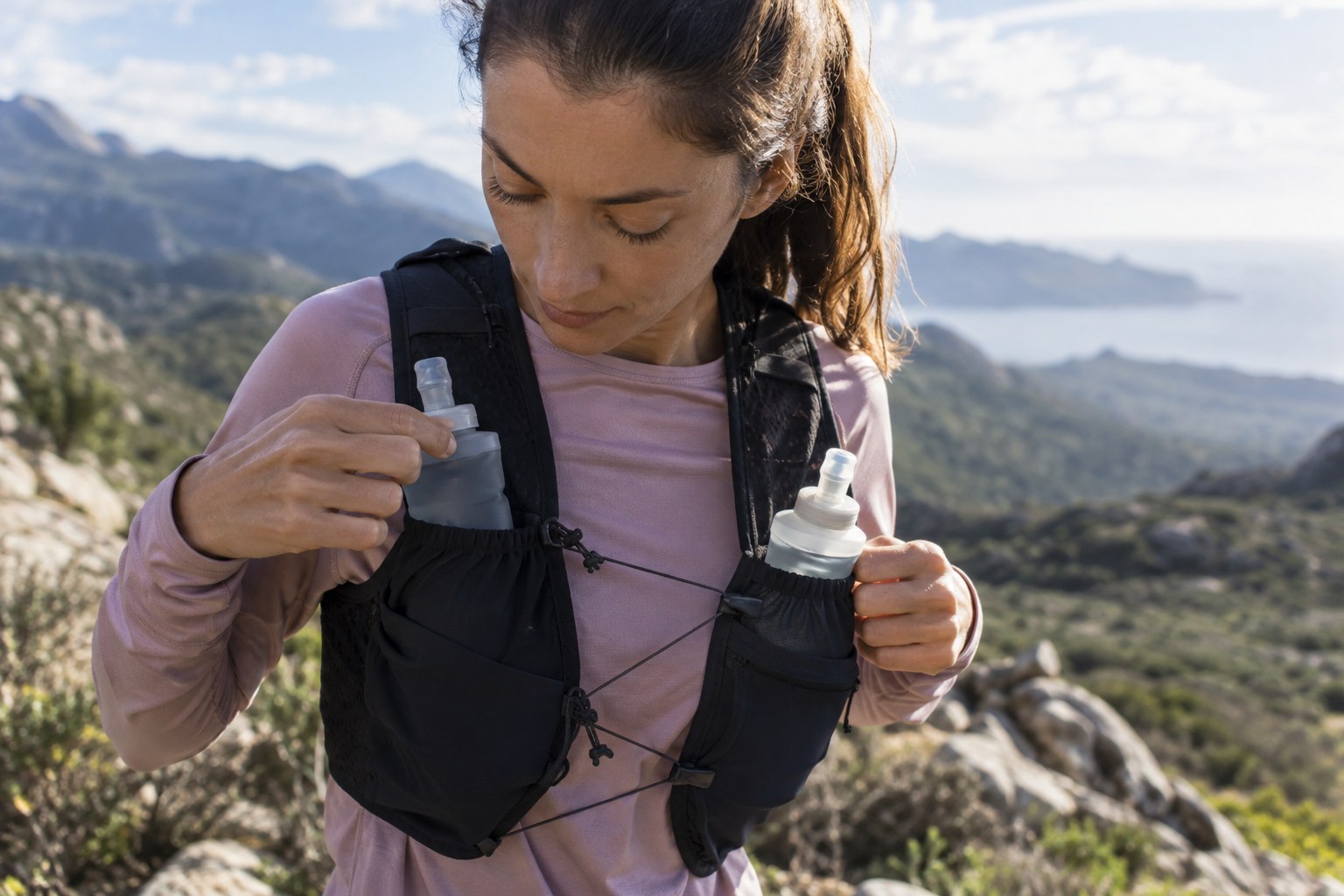 Two soft flasks beside the front pockets of a running vest.