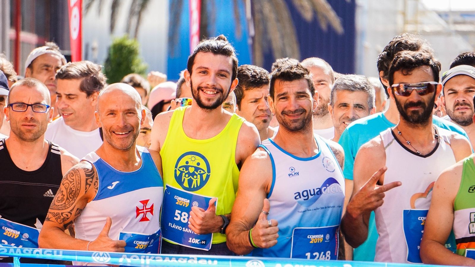 Runners gather closely together behind a starting line.