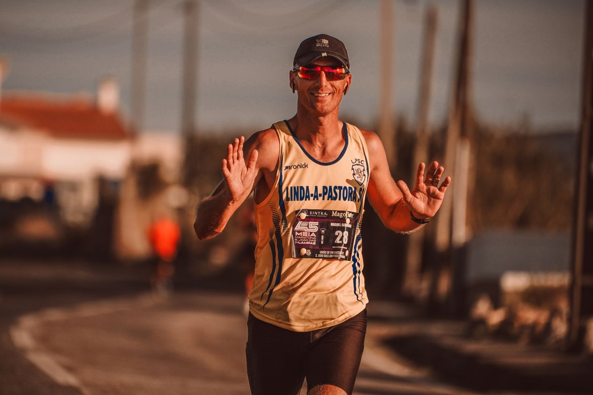 A race participant smiles and lifts both hands for the camera.