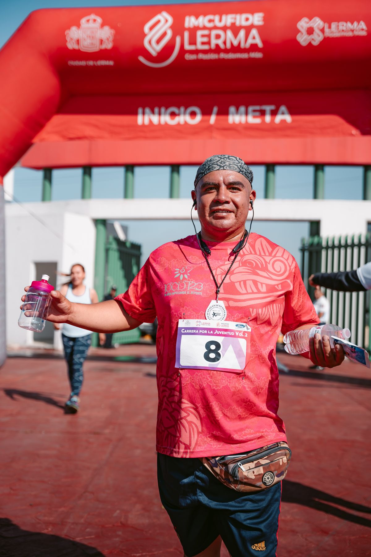A race participant stands beneath a red finish arch.